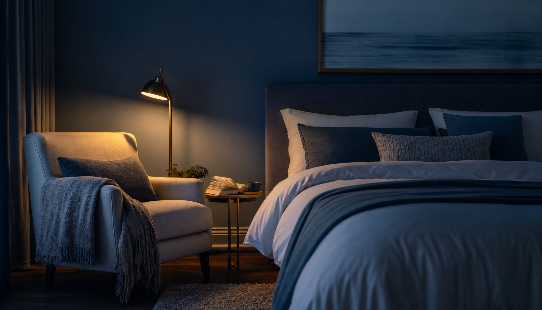 A softly lit reading chair beside an undisturbed bed at night